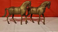 Front view of the pair of large brass horses showing full body with detailed engravings.