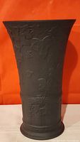 Full front view of Wedgwood black basalt vase showing embossed botanical vine design on matte black ceramic.