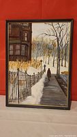 Full view of the framed oil painting showing a woman walking on the sidewalk beside an iron fence covered with snow.