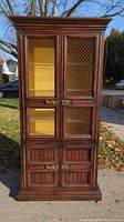 Front view of the 19th century French mahogany bookcase cabinet showing wire mesh glass doors, solid lower wood doors, brass handles, and cornice molding.