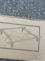 Box showing diagram of black metal adjustable bed frame with caster wheels for twin, full, queen sizes.