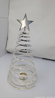 Metal spiral Christmas tree candle holder showing full shape with star on top, placed on white backdrop.