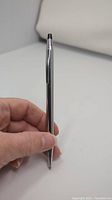 Chrome Cross pen held in hand showing slender polished chrome body and retractable tip.