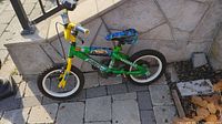 Full side view of the green Hot Wheels kids bicycle showing the frame, tires, saddle, and decals.