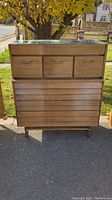 Front view showing six-drawer oak tall chest with louvered fronts, glass top and tapered legs