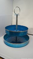 Side view of the two-tiered serving tray showing the blue metal trays and chrome central rod with handle.