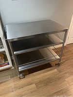 Front view of stainless steel cart showing top surface and two lower shelves