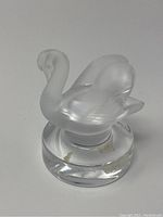 Front and side views of frosted Lalique swan figurine with clear base. Adhesive residue visible on base.