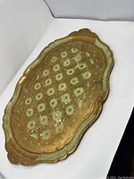 Oval wooden tray painted gold and green with red dots, showing top surface and handles.