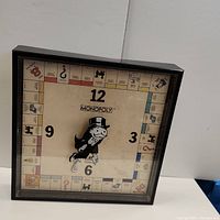 Full view of the square vintage Monopoly board clock with Mr. Monopoly clock hands, showing overall condition and dirt inside the face.