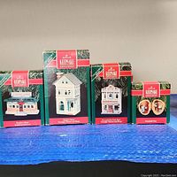 Four Hallmark Keepsake ornaments in their original boxes including Donder's Diner, Hudson House, Prescott Town Court House, and Nashville Chow dog face pair