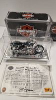 Front view of the Harley-Davidson model motorcycle in clear display case with certificate of authenticity and display box.