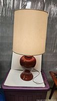 Leviton table lamp with reddish brown ceramic base and beige shade, front view showing overall condition and cord.