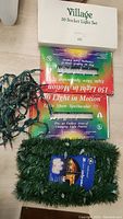 Boxed Village 20 socket Christmas light set with green wiring, along with unopened packets of Light Show Spectacular 150 light in motion light set.