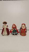 Front view of three Madame Alexander dolls side by side on a white background, highlighting their attire and details.