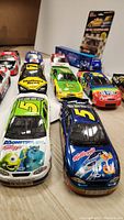 Front row of Nascar diecast cars including Kellogg's #5 and Monsters Inc themed car, showing detailed sponsor logos and colorful paint schemes
