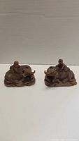 Front view of two brown ceramic buffalo figurines with riders