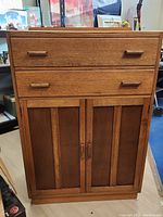 Front view of the vintage wooden dresser with two drawers above a double door cabinet