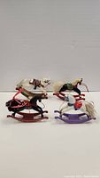 Four miniature vintage Hallmark rocking horse ornaments showing variety in color and details