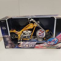 Front view of yellow Ragin Rodz motorcycle toy in box with flame decals and chrome accents, box missing plastic cover.