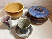 Photo showing all five ceramic items together on a white surface: a lidded casserole, two bowls, and two vases.