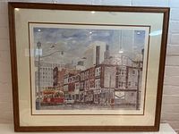 Full view of framed print showing urban street scene with buildings, streetcar, and signage.