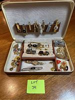 Overview of fitted case containing tie bars, cuff links and lapel pins