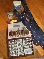 Overview of men’s accessories including ties, cufflinks, tie pins, and boxes arranged on a wooden surface.