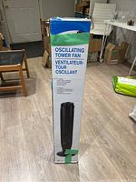Photo of original packaging box of the black oscillating tower fan showing product name and features.
