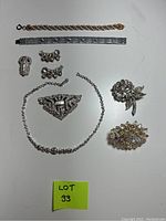 Full view of all jewelry pieces laid flat on white background with lot number visible. Includes two bracelets, two brooches, necklace, and two pairs of earrings.