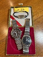 Three watches displayed on a red and white fabric-lined box: a small ladies Gruen Precision watch with black strap, and two men's watches with stainless steel bracelets, Seiko and Fossil. Yellow lot tag 'Lot 37' present.