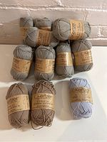 Overall view of all 14 balls of Kertzer yarn arranged in layers showing color variation and labels.