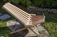 Photo showing side angle of cedar stick chair outdoors on stone and grass, highlighting chair construction and woodworking details.