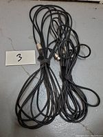 Two black XLR cables coiled with cable ties lying on a grey surface, labeled with number 3.