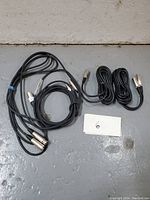 Four black XLR cables coiled on floor with four silver metal connectors visible, organized with cable ties, accompanied by a label with number 6