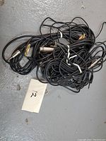 Pile of tangled black cables with XLR female and 1/4 inch male ends, labeled with a paper '12'