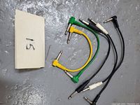 Lot of five short patch cables in various colors with 1/4 inch connectors on a gray surface with label "15"