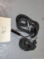 Coiled and straight black audio extension cables, showing 1/4" and 1/8" connectors and partial cable length with connector details.