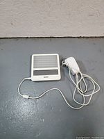 Philips branded square white light therapy device panel with power cord and adapter on gray floor
