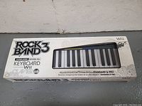Front of the original box showing Rock Band 3 Wireless Keyboard for Wii, includes text about compatibility with Standard & Pro modes.