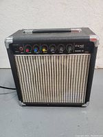 Front view of small black Ross Fame 10 guitar amplifier showing control knobs, speaker grille, and carry handle.