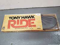 Front of the Tony Hawk Ride game box for Wii showing the wireless skateboard controller partially visible inside the box.