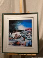 Full view of original framed artwork showing a snowy village scene with multiple houses and human figures under a colorful sky.
