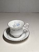 Teacup and saucer front view showing floral pattern and silver trim