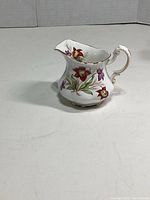 Side view of Paragon porcelain creamer pitcher displaying the hand-painted pitcher plant floral design and gold trim detail on handle and rim.