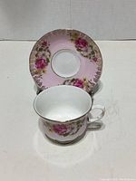 Front view of Queen Anne teacup and saucer set showing pink floral design and gold trim.