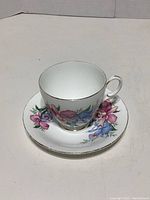 Photo showing the fine bone china teacup on its matching saucer, highlighting the floral pattern and gold trim.