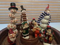 Photo of assorted Santa and snowman figurines grouped together in baskets showing variety of styles and sizes.