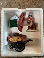 Colorful Dept 56 Chelsea Flowers miniature flower cart with pink and green umbrella and flower vendor figurine in molded styrofoam packaging, in mint condition.