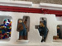 Top view showing three porcelain figurines and fairy lights with red folding ladder inside foam packaging